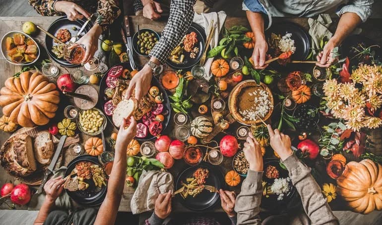 People eating and drinking wine at Thanksgiving celebration dinner table