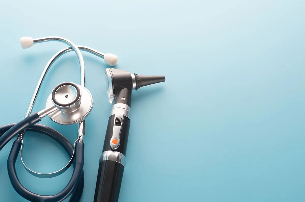 Otoscope with stethoscope on blue background.
