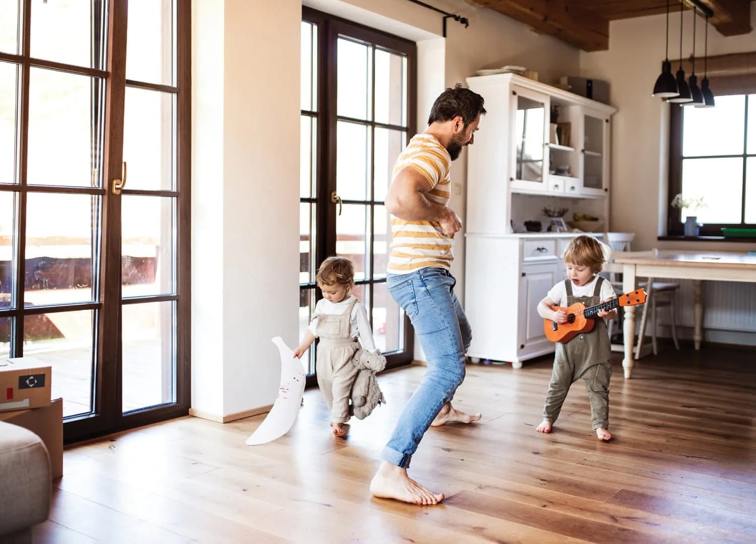 A father and toddler children playing indoors at home.