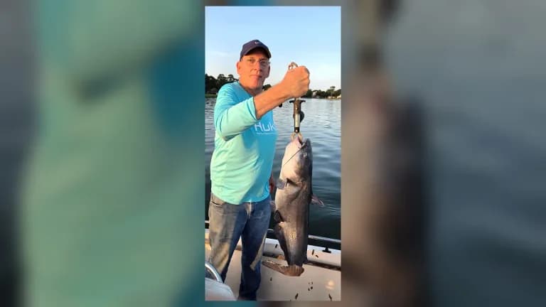 Steven holds a large Lake Conroe catfish from a boat during warm evening light