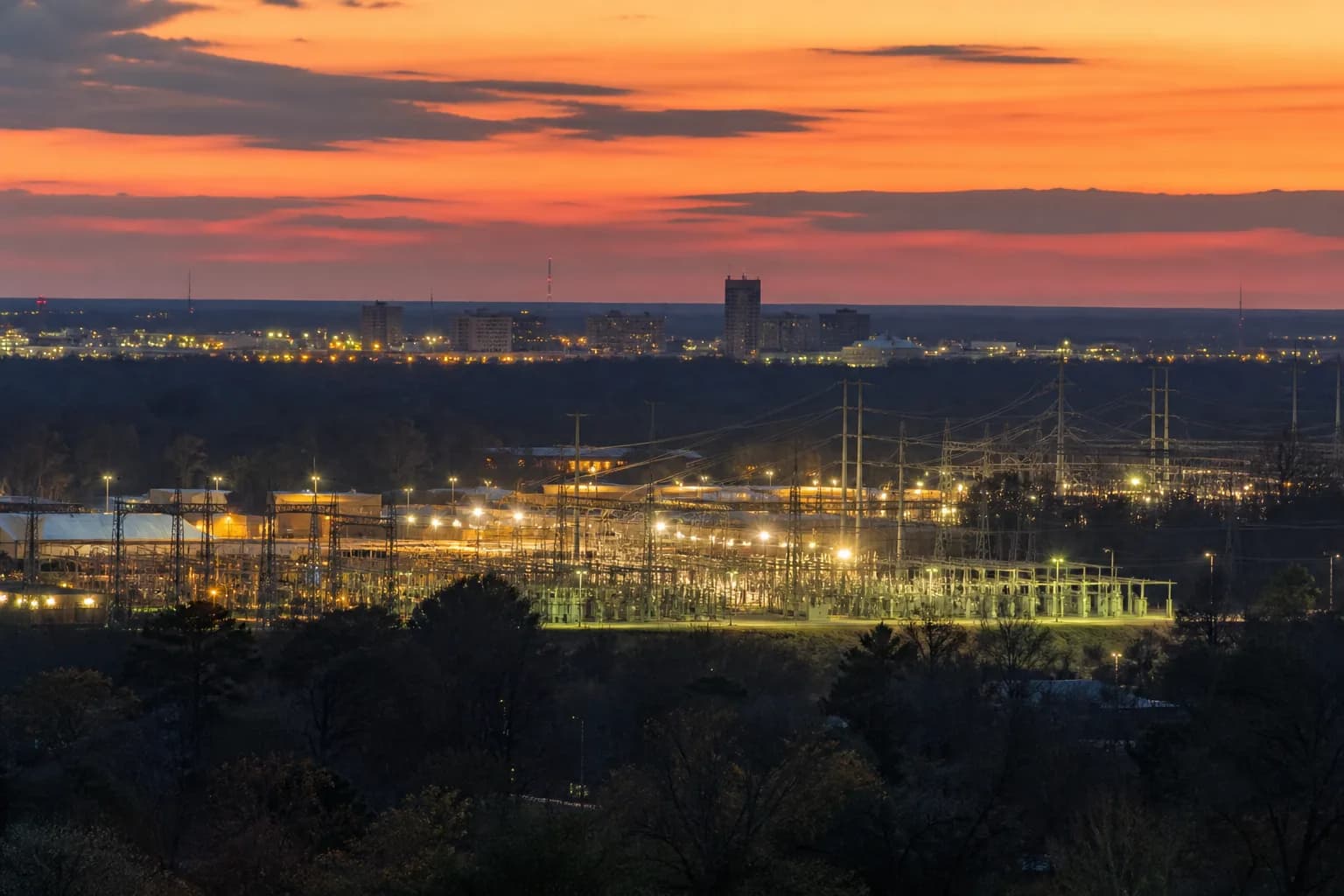 Transmission lines and substations at the edge of a growing Texas city at dusk