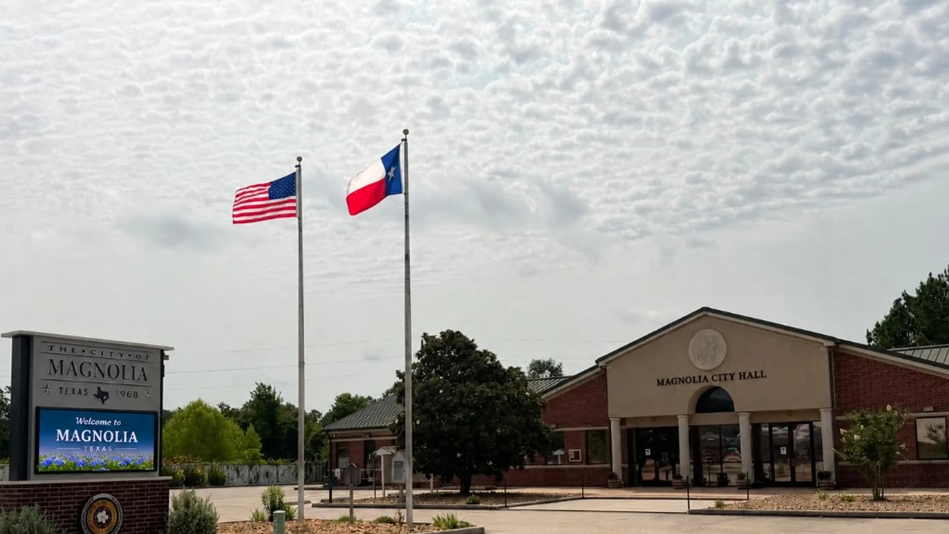 Magnolia City Hall with the City of Magnolia Texas 1968 monument sign and flags