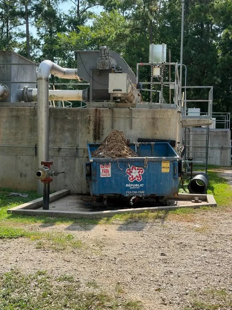 A Republic Services dumpster overflowing with brown waste at a Magnolia-area water treatment plant