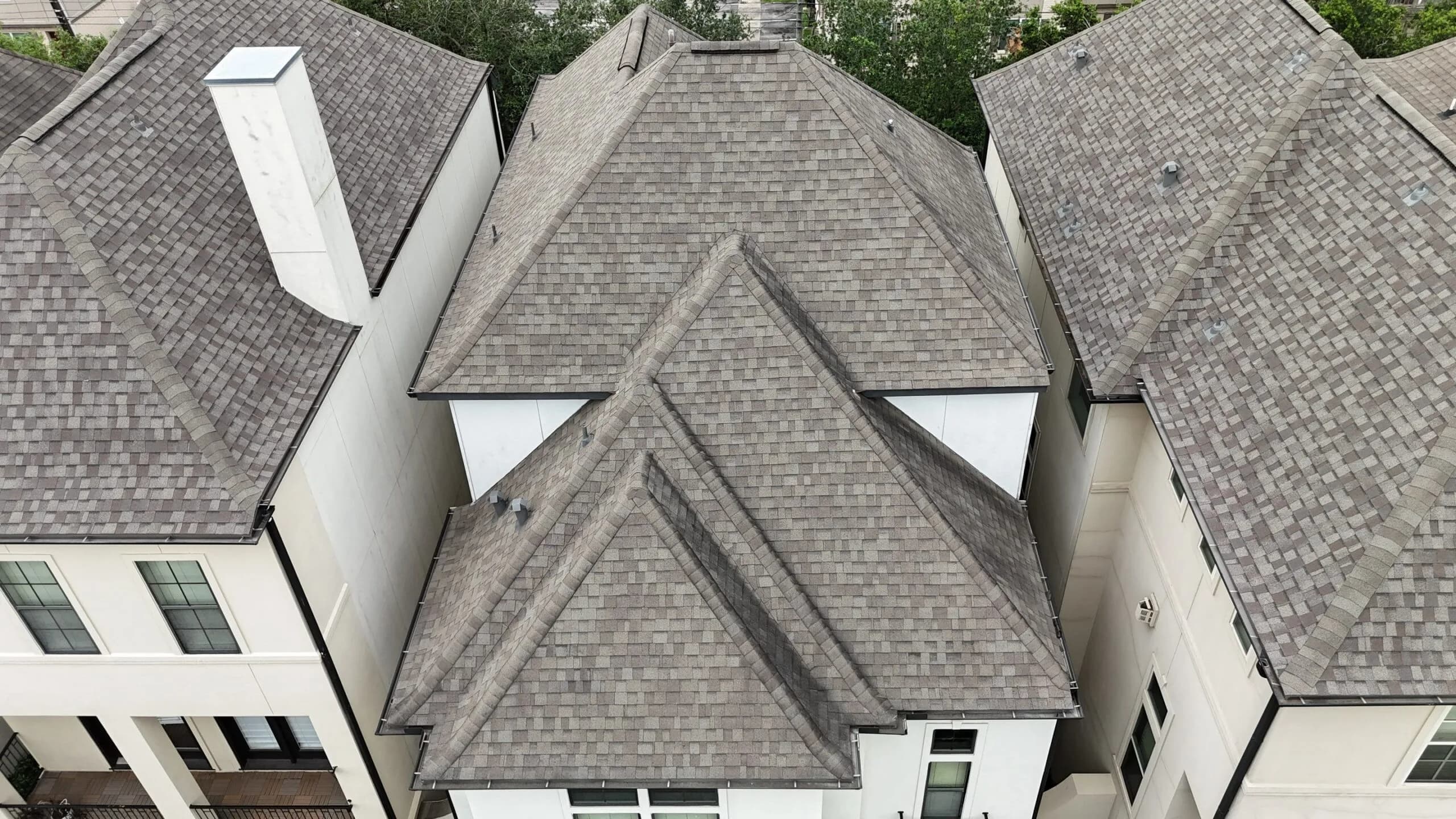 A light gray dimensional roof on a townhome, between neighboring shingle roofs.