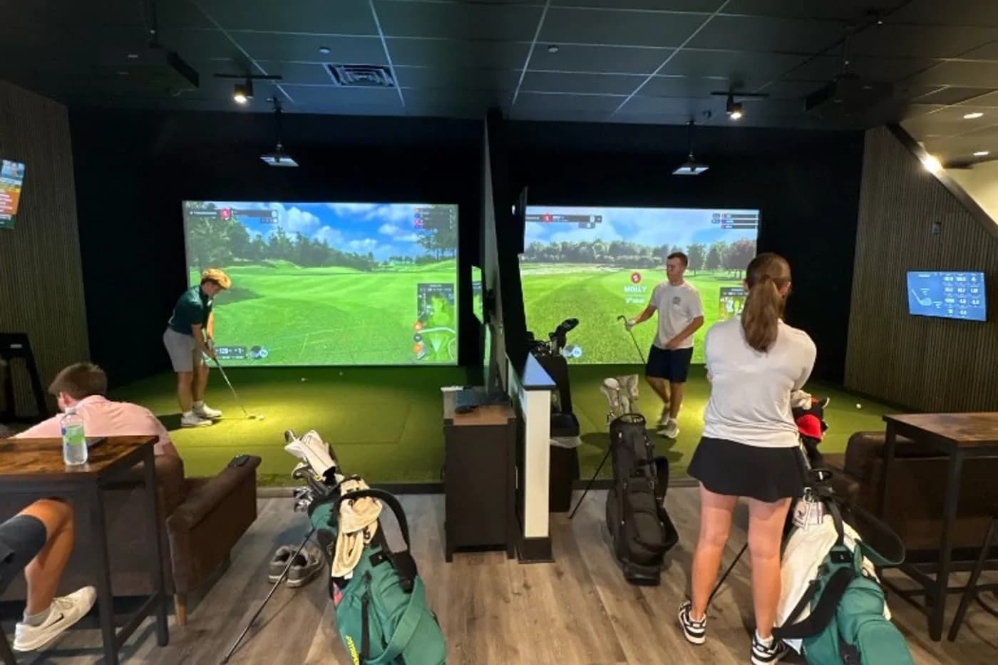 Golfers hitting in TrackMan simulator bays at Flight Indoor Golf in Hockessin