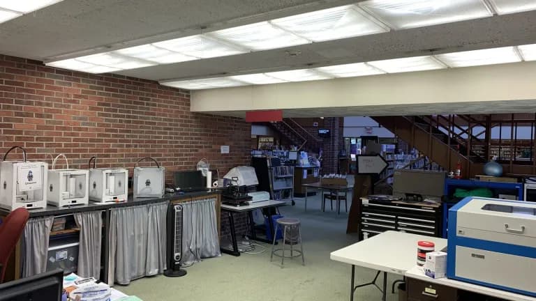 Several 3D printers on a counter in a public library makerspace