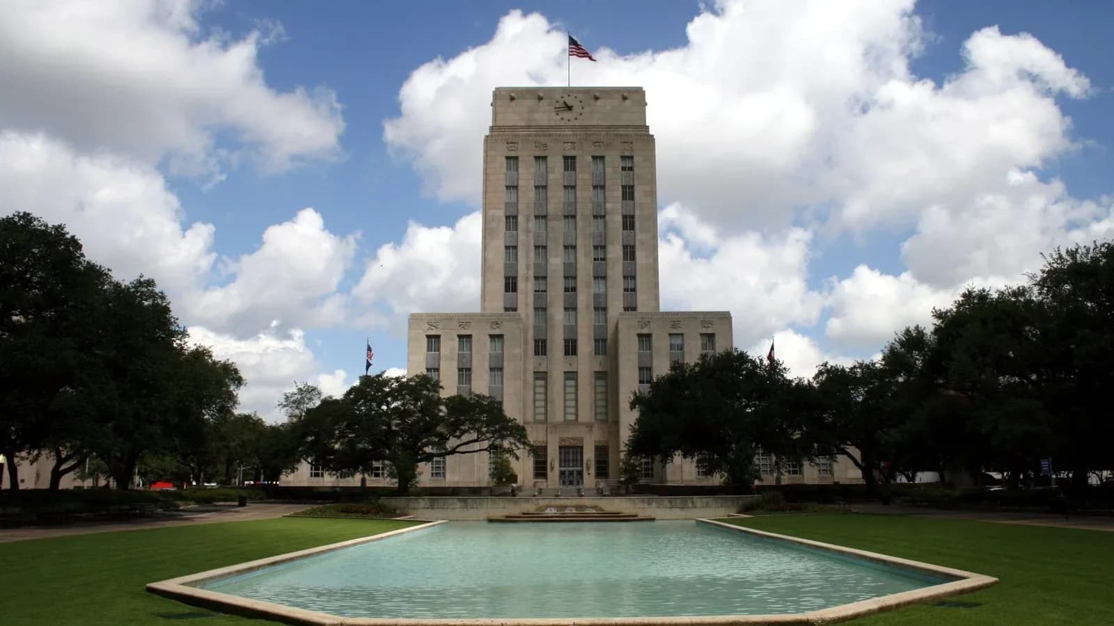 Houston City Hall, a tall limestone tower, behind the reflection pool in Hermann Square