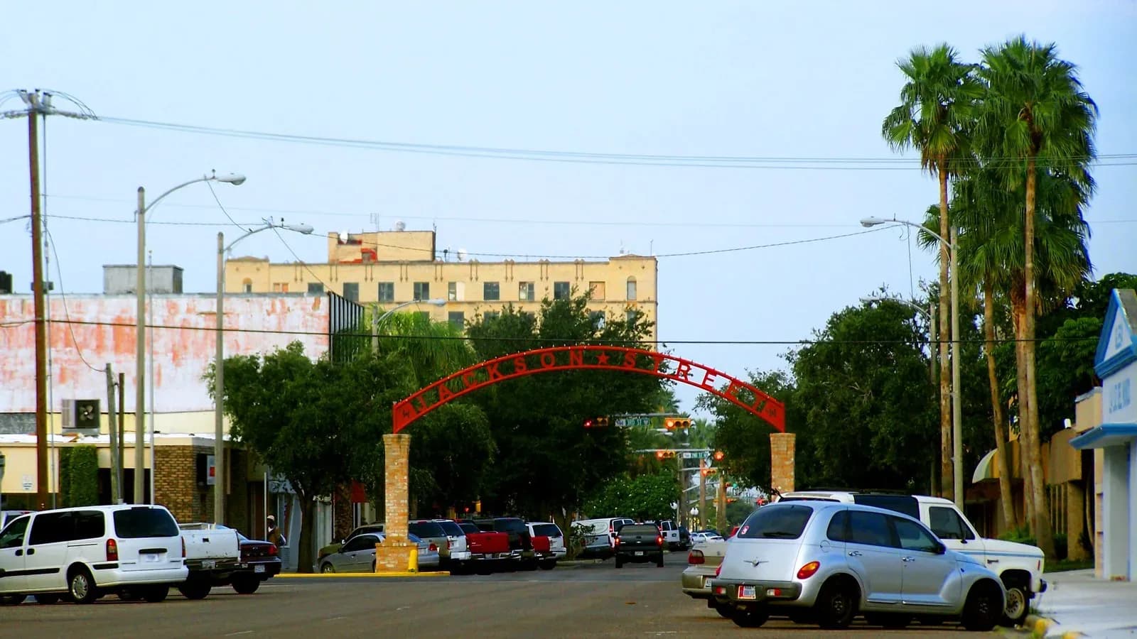 A red arch over Jackson Street in downtown Harlingen, framed by palm trees
