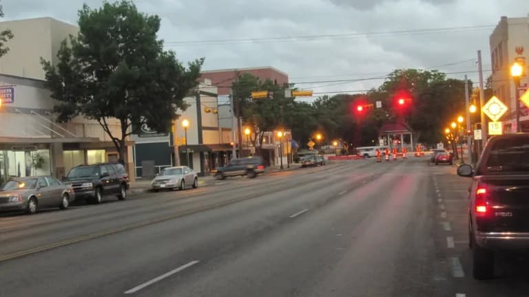 A quiet downtown New Braunfels street at dawn with traffic signals glowing red
