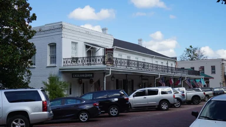 The white two-story Excelsior House hotel with an iron balcony on a brick street in Jefferson