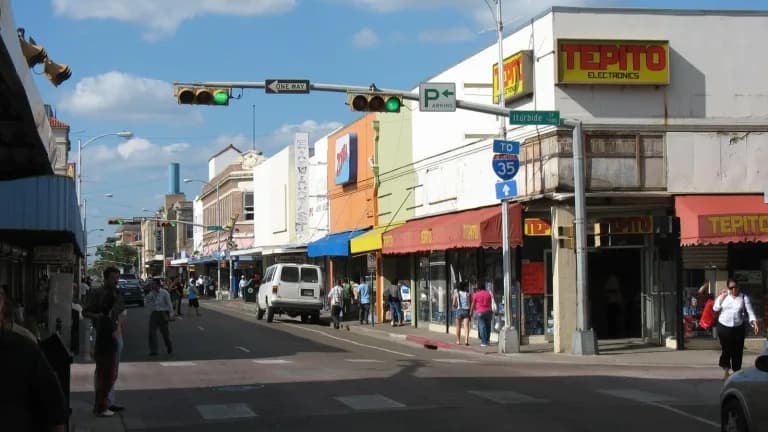 Shoppers walk past storefronts on a downtown Laredo street corner