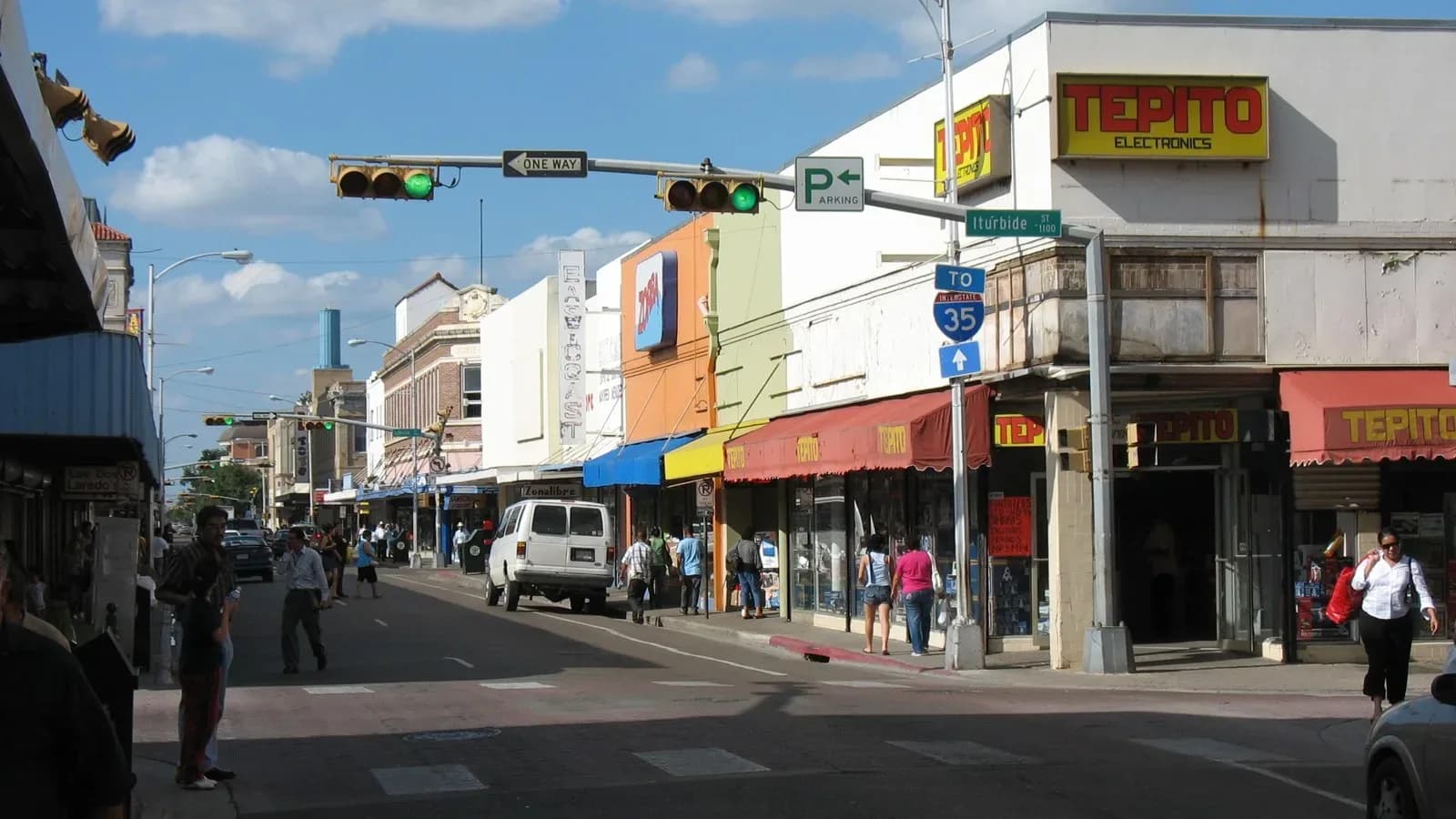 Shoppers walk past storefronts on a downtown Laredo street corner