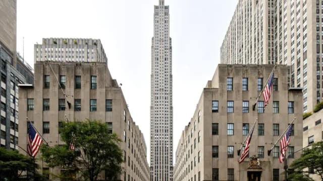30 Rockefeller Plaza rising between two stone buildings flying American flags