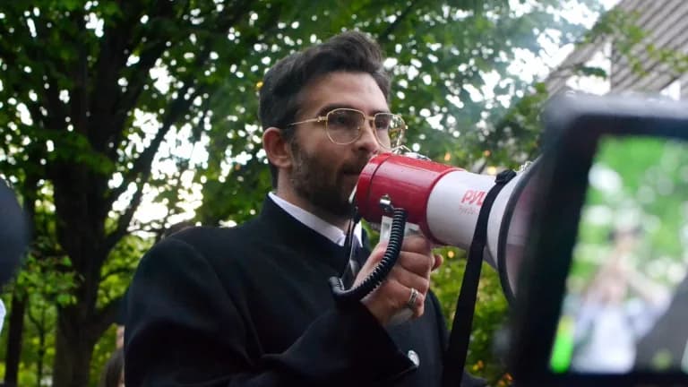 Hasan Piker speaking into a megaphone at an outdoor rally