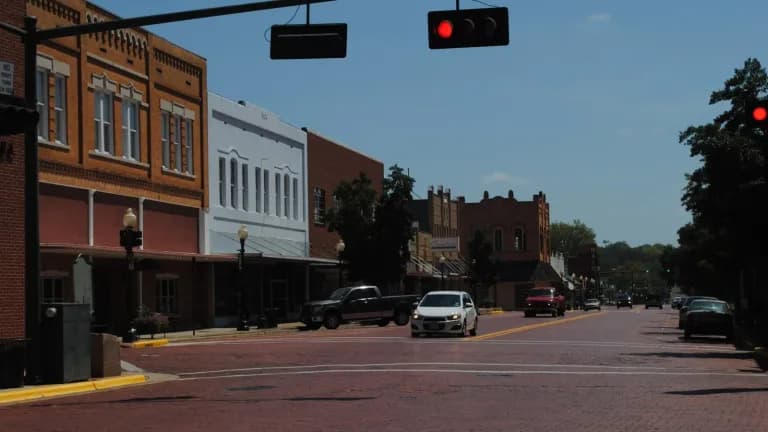 A brick street in downtown Nacogdoches lined with two-story historic storefronts under a blue sky