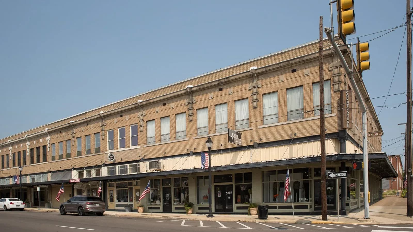 A long two-story brick commercial building on a corner in downtown Paris, Texas, with American flags along the sidewalk