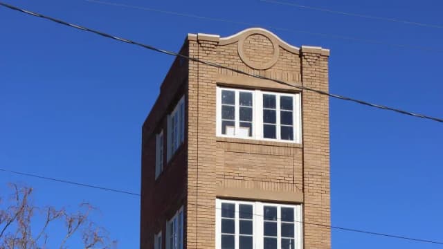The narrow four-story brick Newby-McMahon Building in downtown Wichita Falls against a blue sky