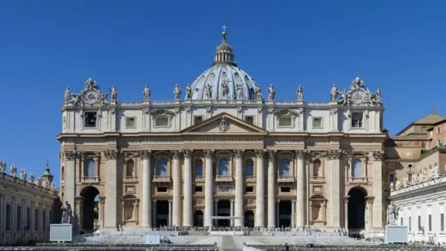 The main facade and dome of St. Peter's Basilica in Vatican City under a clear blue sky