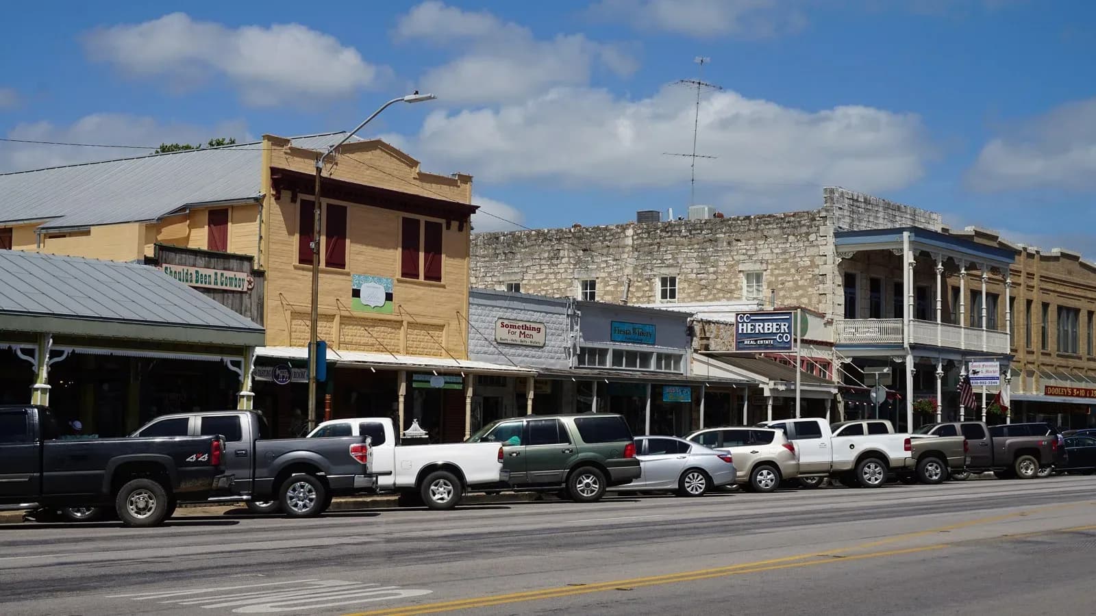 Historic stone and wood storefronts along East Main Street in Fredericksburg with pickups parked at the curb