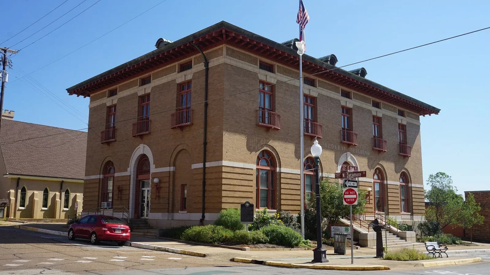The two-story tan brick Post Office and Federal Building in Palestine with an American flag out front