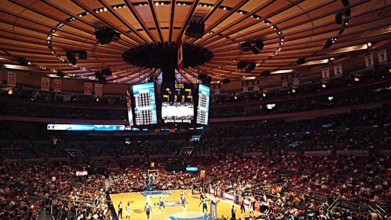 Wide view of a packed Madison Square Garden arena under its round ceiling and center-hung scoreboard