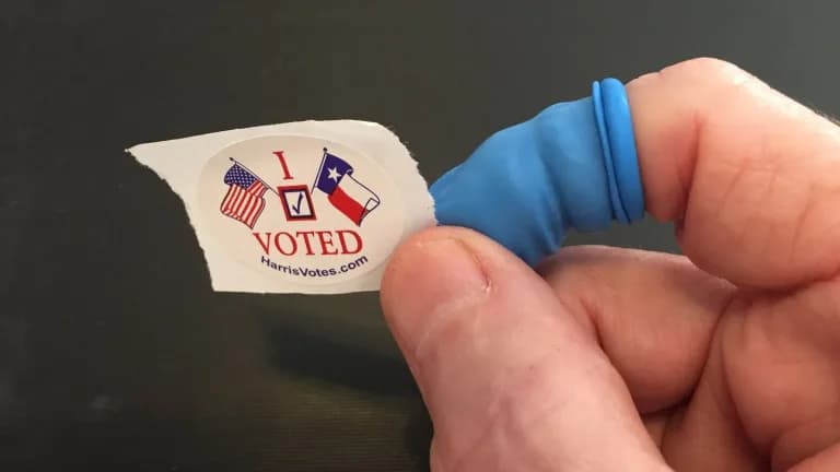 A Harris County I Voted sticker held between a voter's fingers
