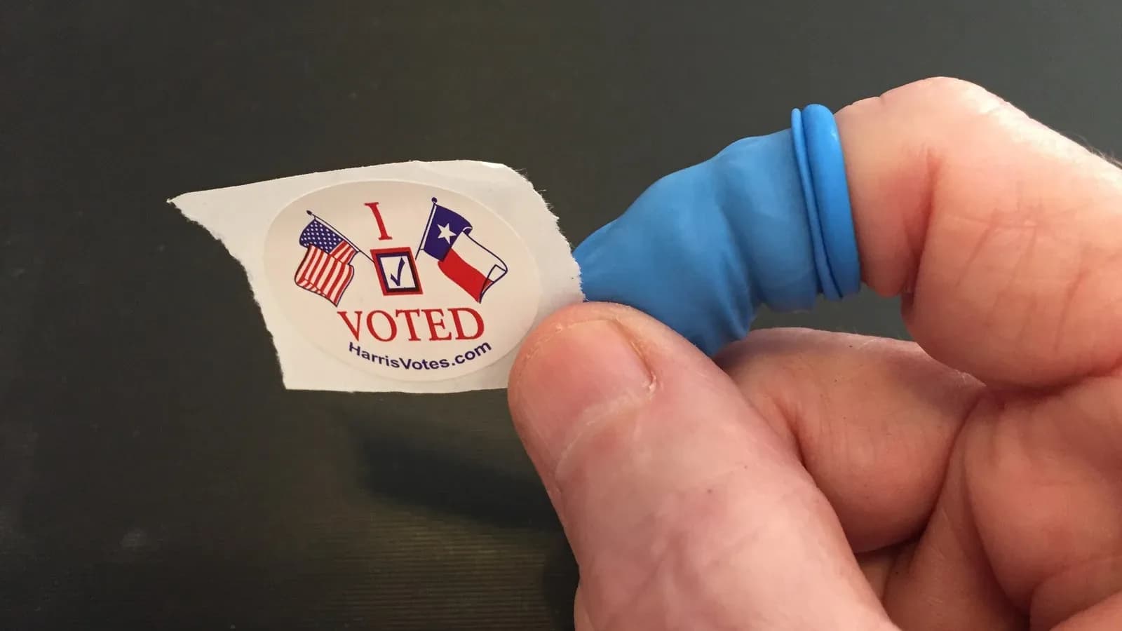 A Harris County I Voted sticker held between a voter's fingers
