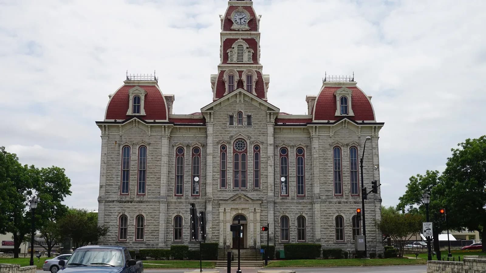 The ornate limestone Parker County Courthouse in Weatherford with red domed towers and a clock tower