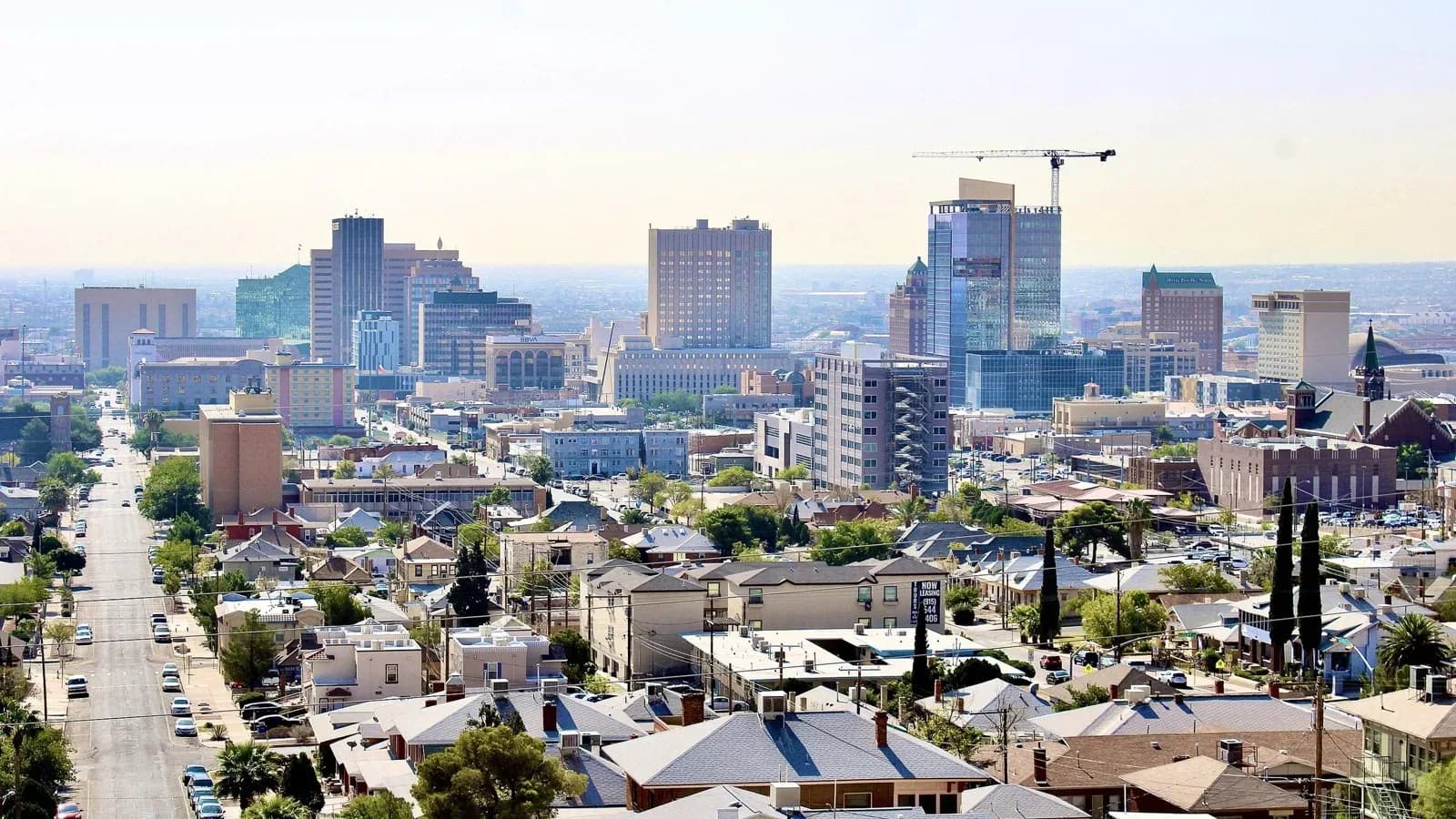Downtown El Paso skyline rising above neighborhoods of low houses and tree-lined streets