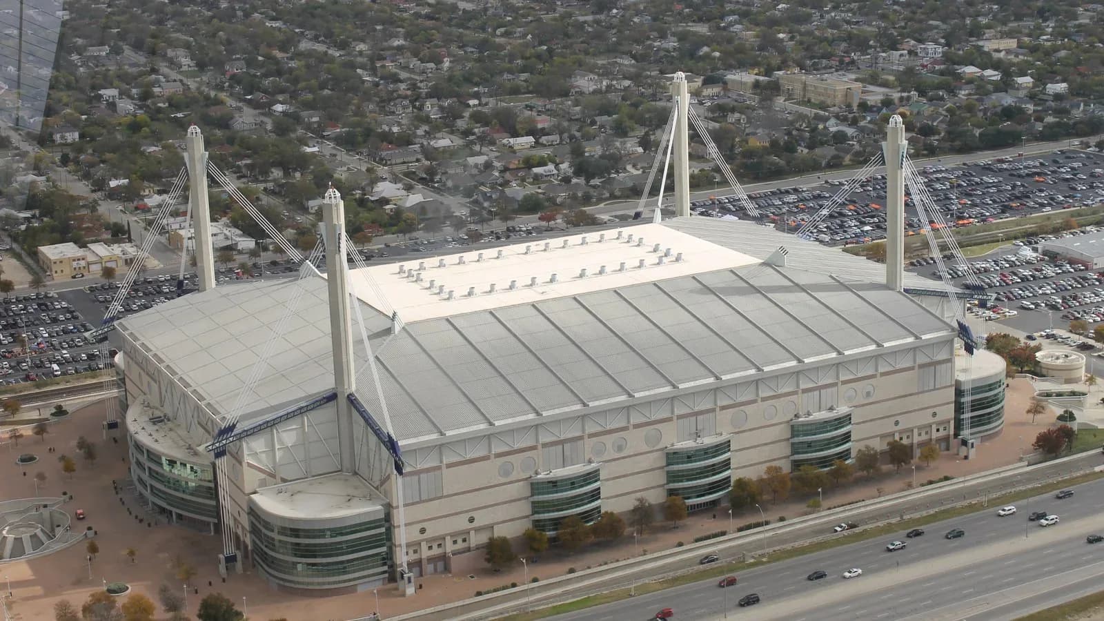 Aerial view of the white-roofed Alamodome stadium in San Antonio with its four tall support towers and surrounding parking lots