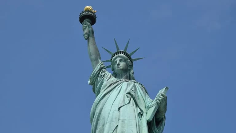 The Statue of Liberty holding her torch aloft against a clear blue sky