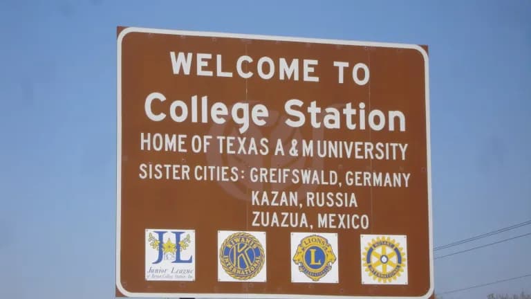 A brown Welcome to College Station sign listing sister cities beside State Highway 6