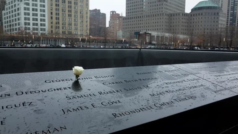 A white rose placed in a victim's name on the bronze parapet of the South Pool at the National September 11 Memorial on a rainy day
