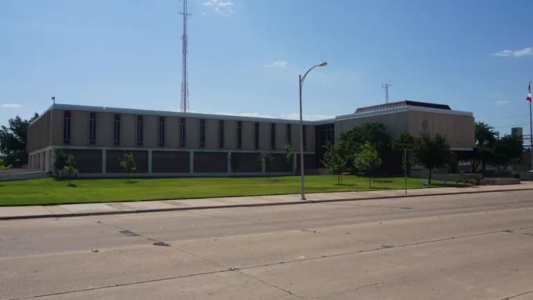 The low, modern Abilene City Hall building across a wide street on a sunny day