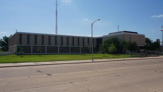 The low, modern Abilene City Hall building across a wide street on a sunny day