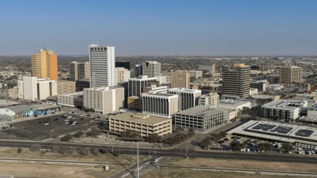 Downtown Midland office towers and parking lots seen from above under a hazy sky