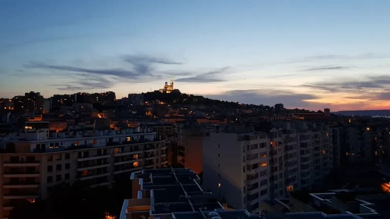 The basilica of Notre-Dame de la Garde lit on its hilltop above the apartment buildings of Marseille, France, at dusk