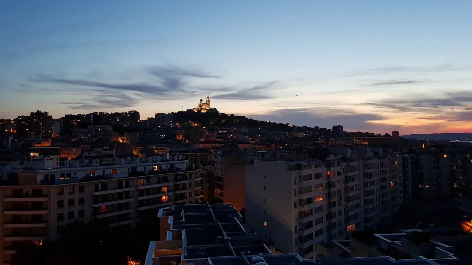 The basilica of Notre-Dame de la Garde lit on its hilltop above the apartment buildings of Marseille, France, at dusk