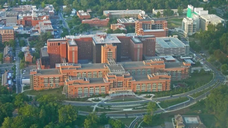 Aerial view of the brick buildings of the NIH Clinical Center on the National Institutes of Health campus in Bethesda, Maryland, surrounded by trees