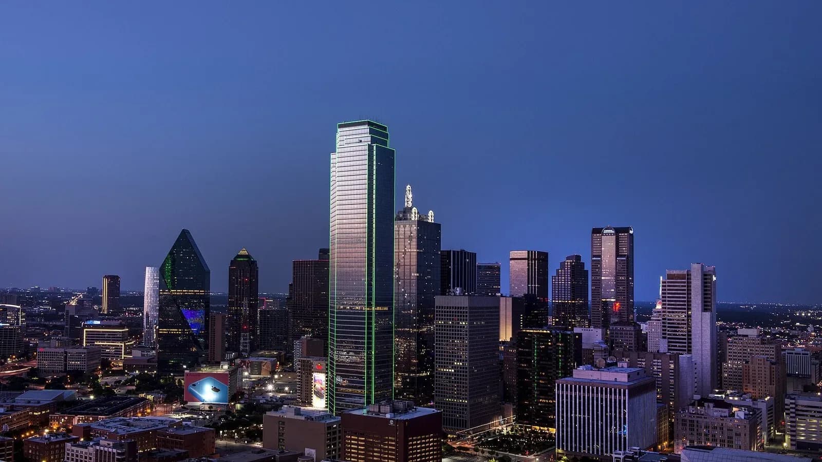 Downtown Dallas skyline at dusk with lighted office towers under a blue evening sky