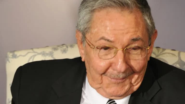 Close-up of an elderly Raúl Castro in glasses, a dark suit and a striped tie, smiling slightly while seated in an upholstered chair