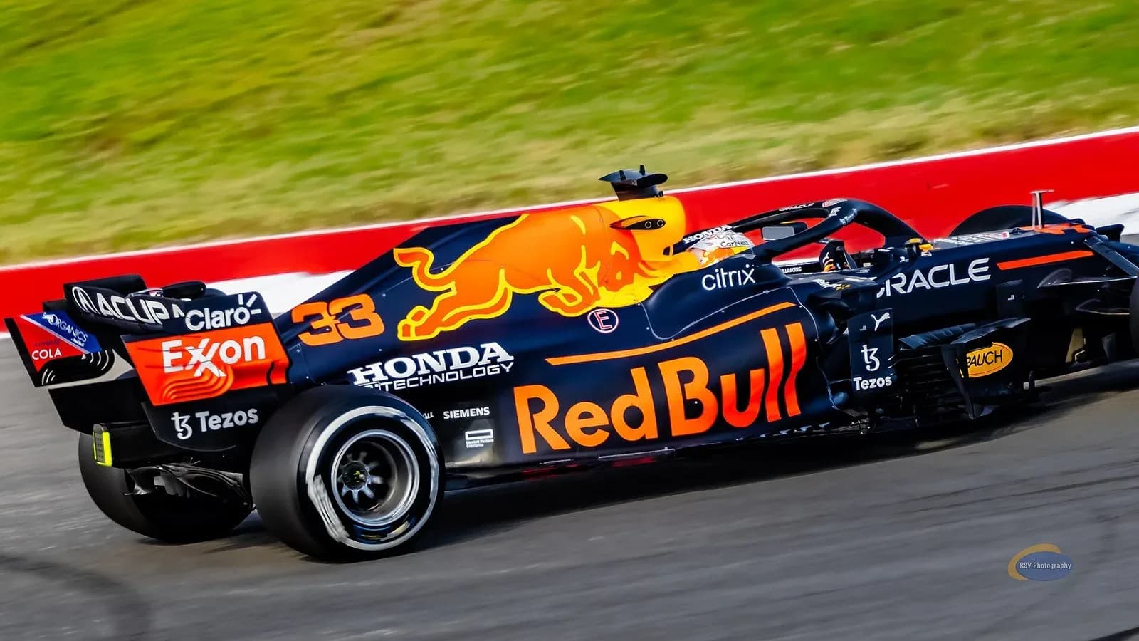 A dark blue Red Bull Formula 1 car with red and yellow livery racing past a curb at Circuit of the Americas