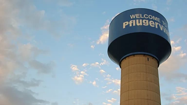 A water tower reading Welcome to Pflugerville against a partly cloudy sky