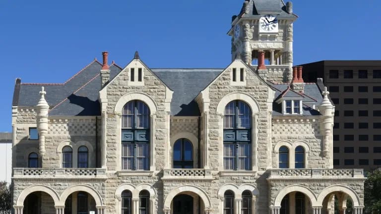 The Old Victoria County Courthouse, a stone building with a clock tower, against a blue sky