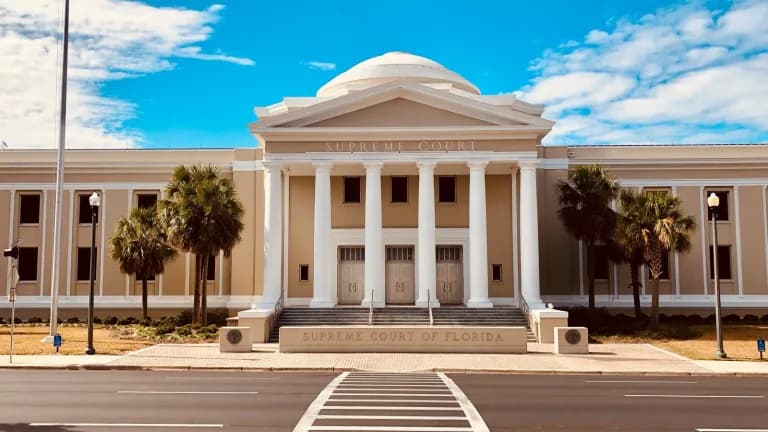 The domed, columned Florida Supreme Court building in Tallahassee under a blue sky with palm trees in front