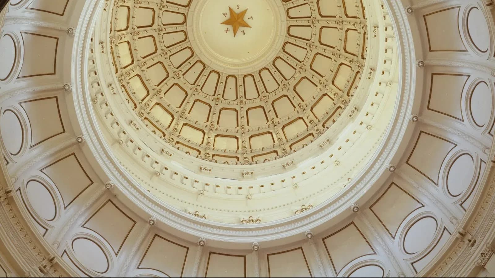 Looking up into the ornate dome of the Texas Capitol rotunda, with a gold star at its center