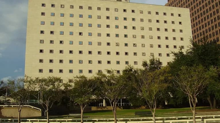 The Bob Casey United States Courthouse, a tall light-colored federal building behind a row of trees in downtown Houston