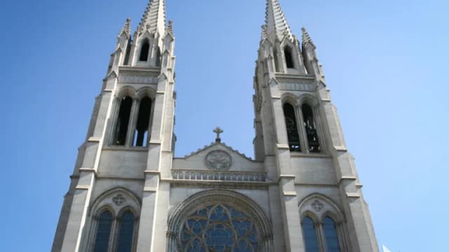 The twin Gothic spires of the Cathedral Basilica of the Immaculate Conception in Denver against a blue sky