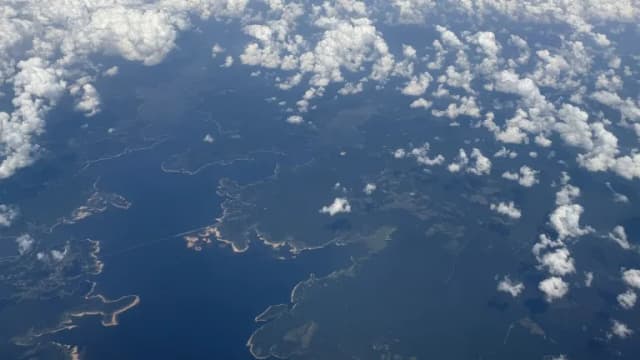 Aerial view through scattered clouds of the winding shoreline of Sam Rayburn Reservoir in East Texas