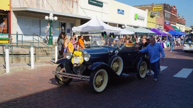 A dark Ford Model A driving in a small-town Texas parade
